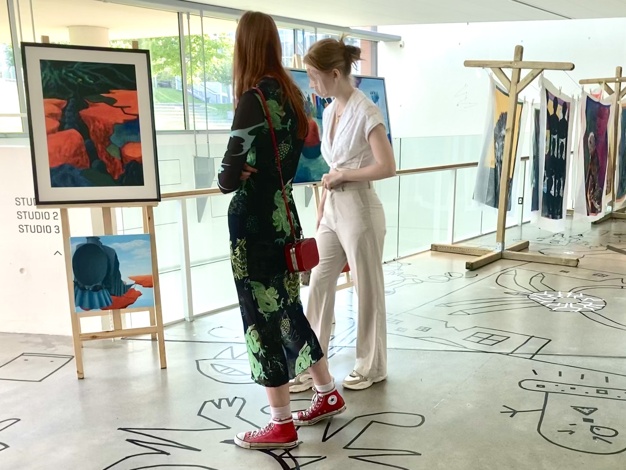 Billede fra Marie Juhls udstilling på ARoS. To kvinder betragter Marie Juhls surrealistiske værker.